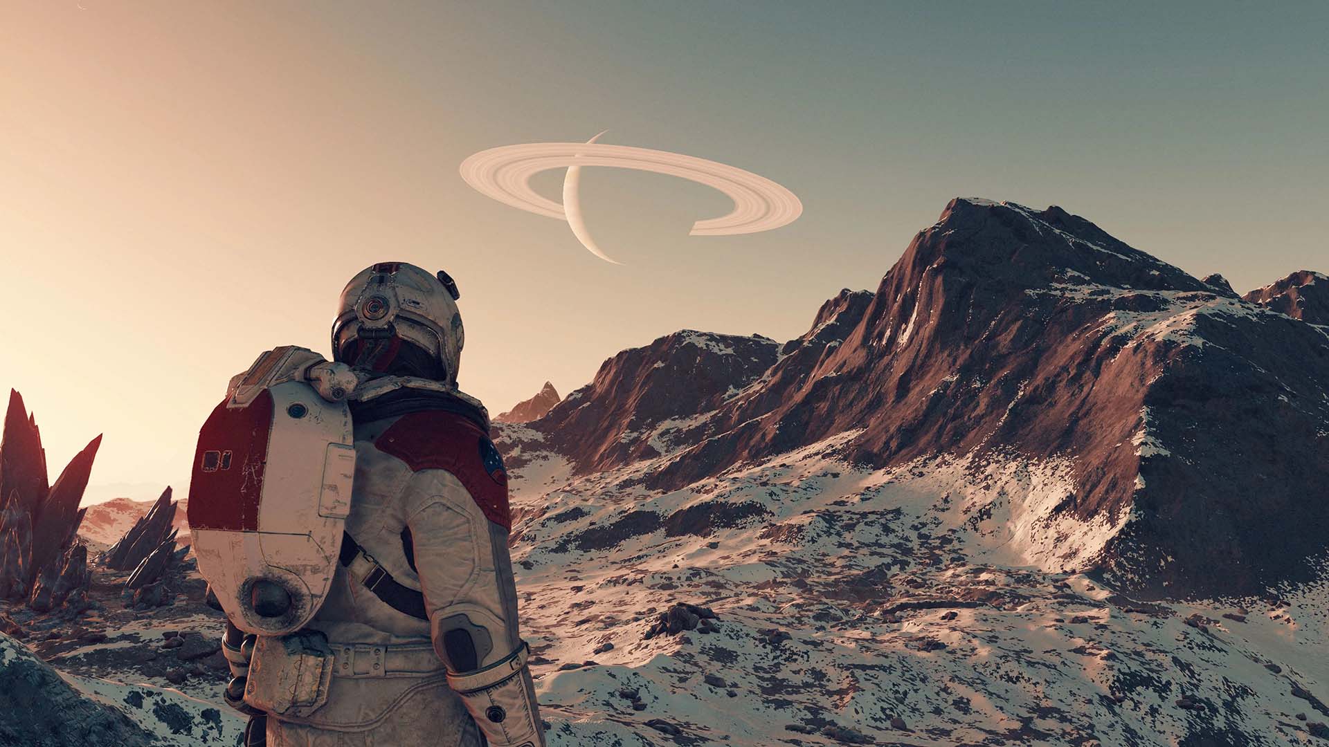 Postava hráče ve hře Starfield se dívá na zasněženou horu, na obloze je vidět vzdálená planeta a její prstence.