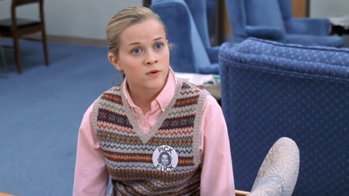 Reese Witherspoon poartă o vestă de pulover și un nasture ca Tracy Flick în Election
