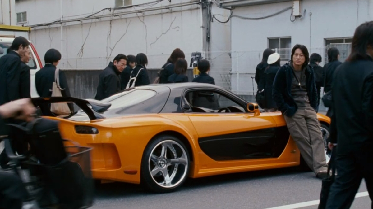 Han se poflakuje na své oranžovo-černé Mazdě ve filmu Rychle a zběsile: Tokijský drift