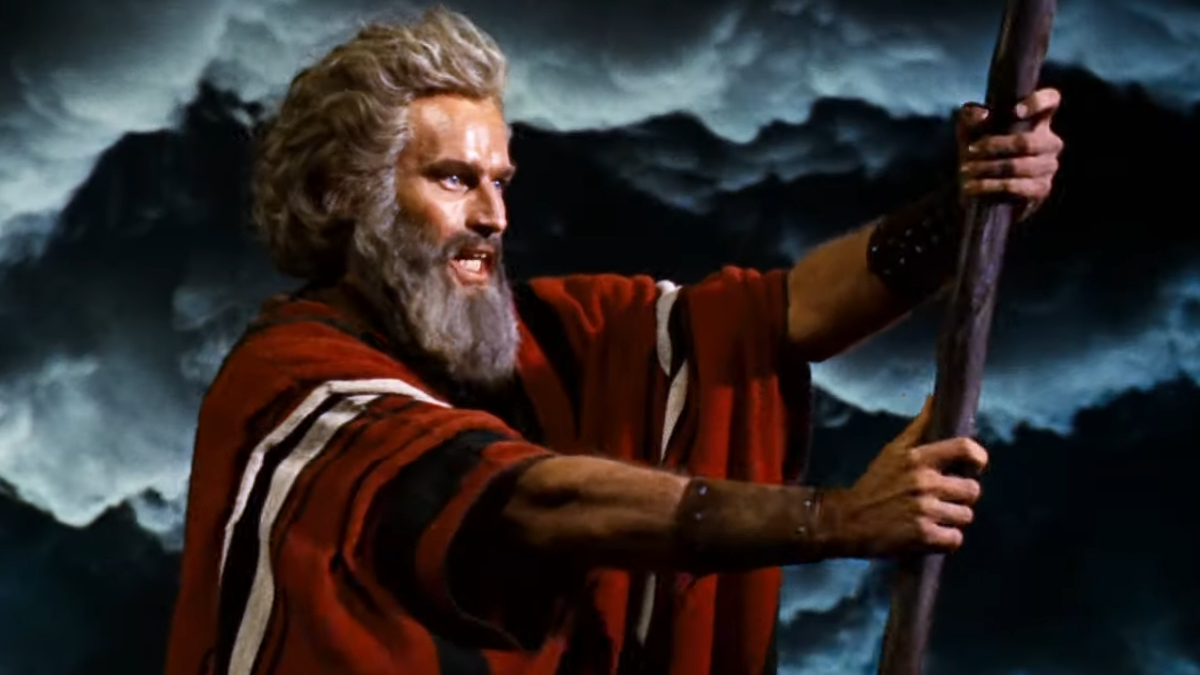 Charlton Heston, no papel de Moisés, segura uma bengala em frente a nuvens de trovoada em Os Dez Mandamentos