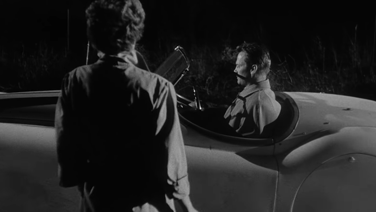 Eine Frau nähert sich einem Mann in einem Cabrio in Kiss Me Deadly