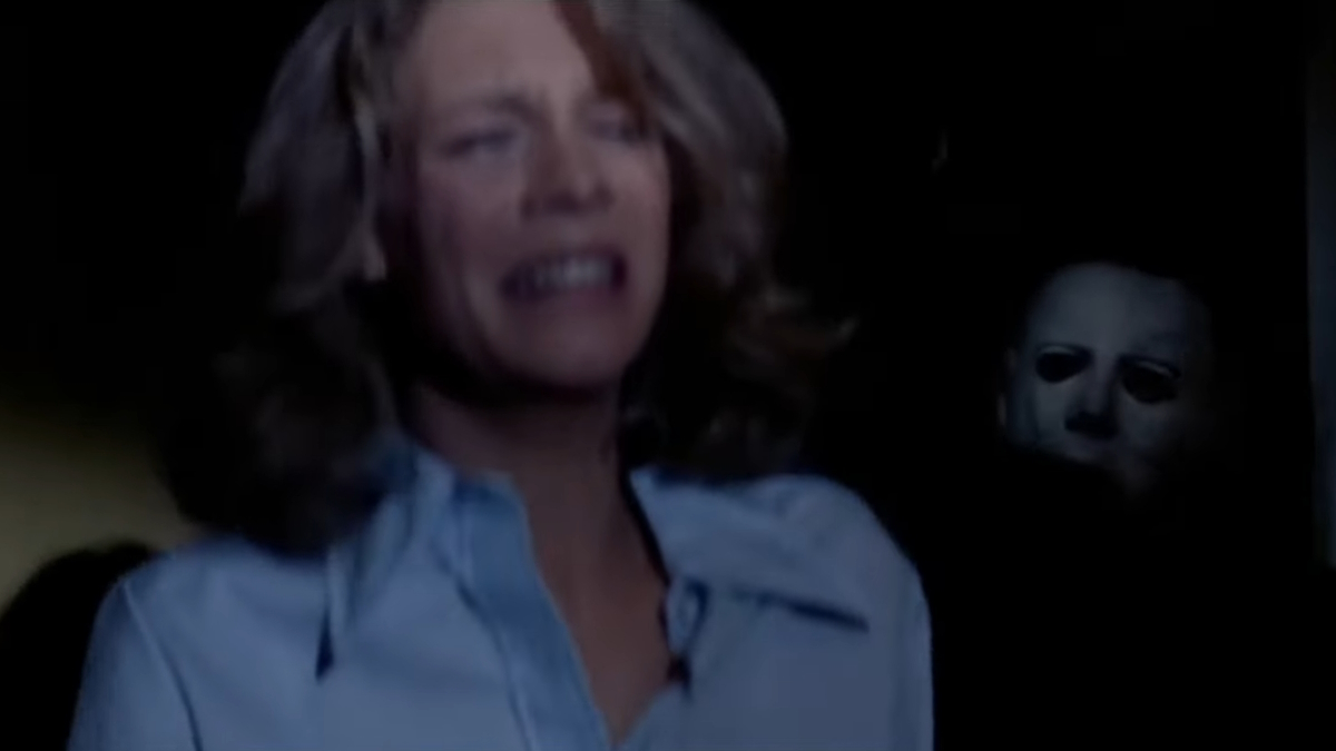 Laurie Strode piange nella sua stanza con Michael Myers che la perseguita da dietro.