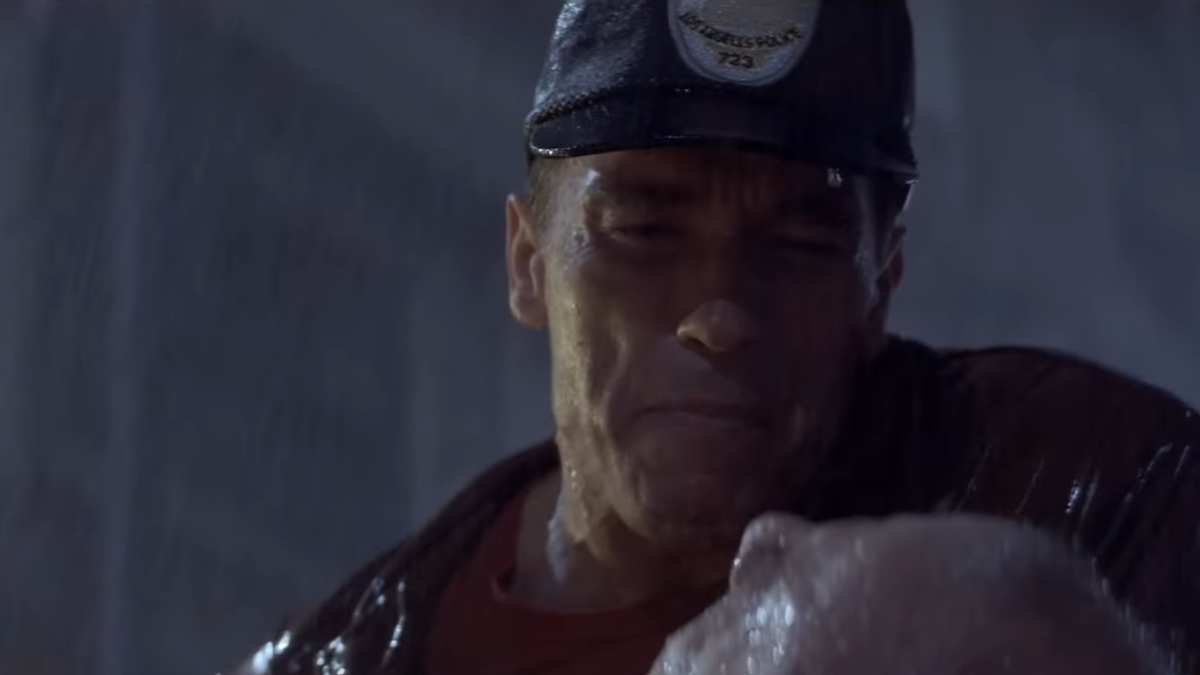 Arnold Schwarzenegger sta in piedi sotto la pioggia in Last Action Hero
