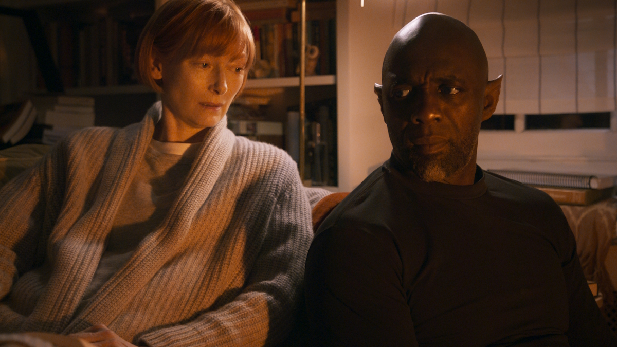 Tilda Swinton e Idris Elba siedono l'uno accanto all'altra in una camera da letto in Three Thousand Years of Longing.