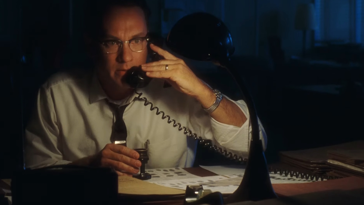 Tom Hanks zvedá telefon ve své tmavé kanceláři ve filmu Chyť mě, když to dokážeš
