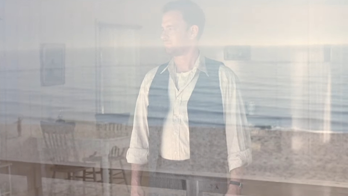 Tom Hanks stojí v místnosti u pláže na konci filmu Road to Perdition (Cesta do zatracení)