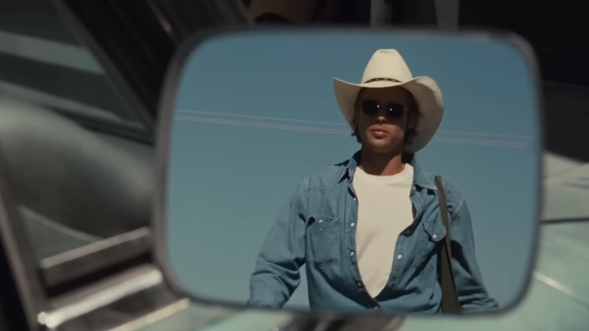 Brad Pitt apare în oglinda laterală a unei mașini purtând o pălărie de cowboy și blugi