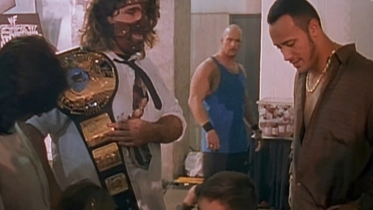 Dwayne Johnson, na pele de The Rock, nos bastidores de um espetáculo da WWF com Mankind e Stone Cold Steve Austin