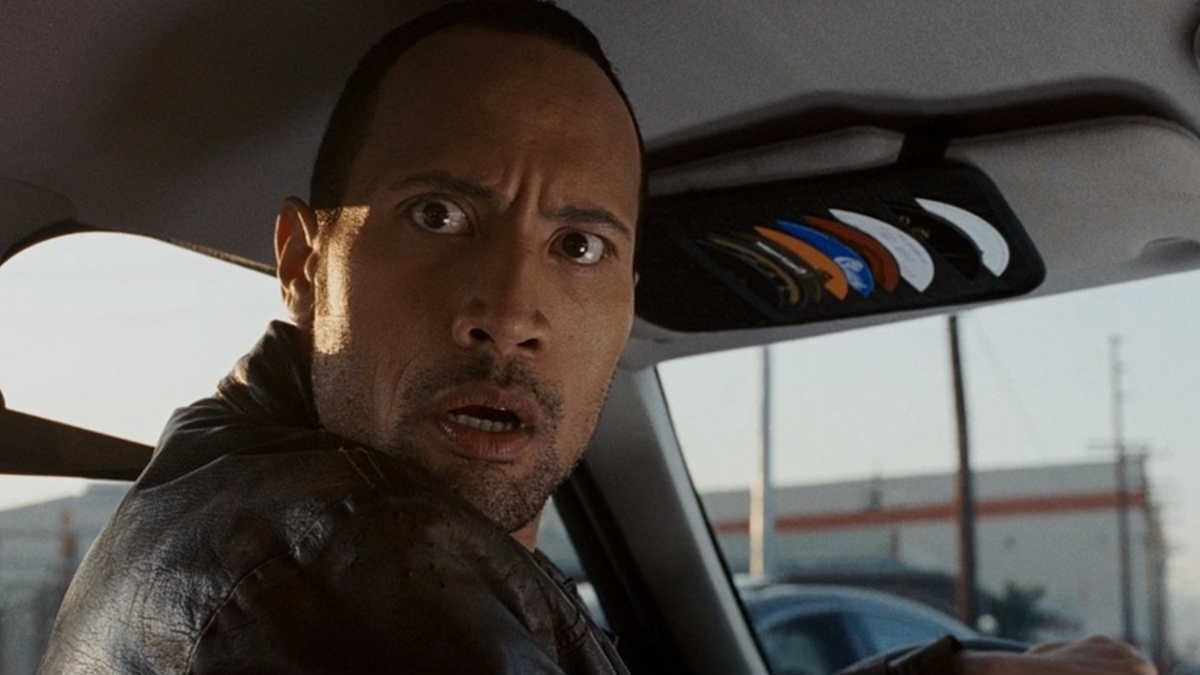 Dwayne Johnson ha una faccia scioccata mentre guarda il sedile del conducente del suo taxi.