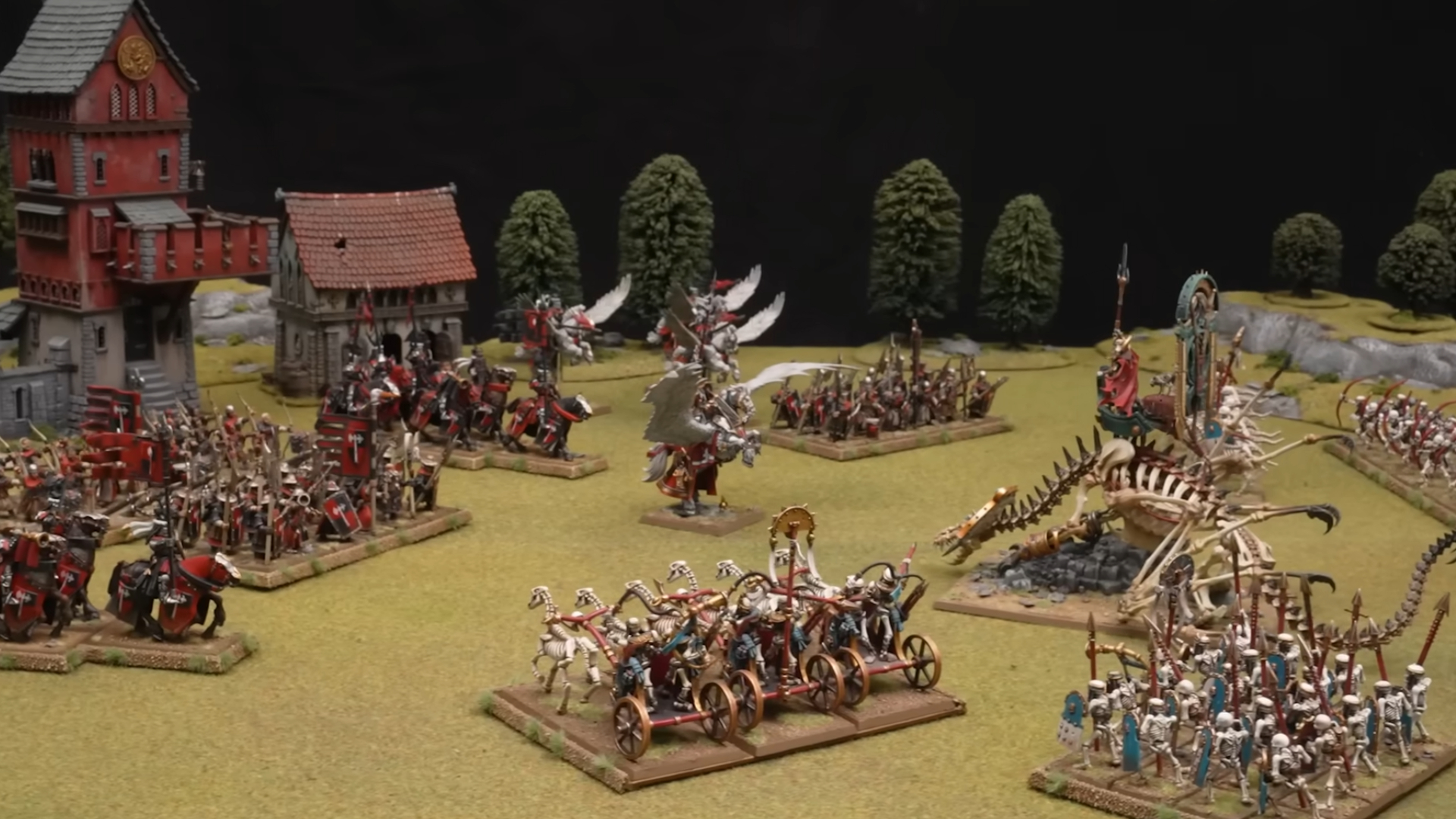 Armáda Bretonců a Hrobových králů se střetává na fantasy bojišti s travnatými poli, stromy a středověkými budovami