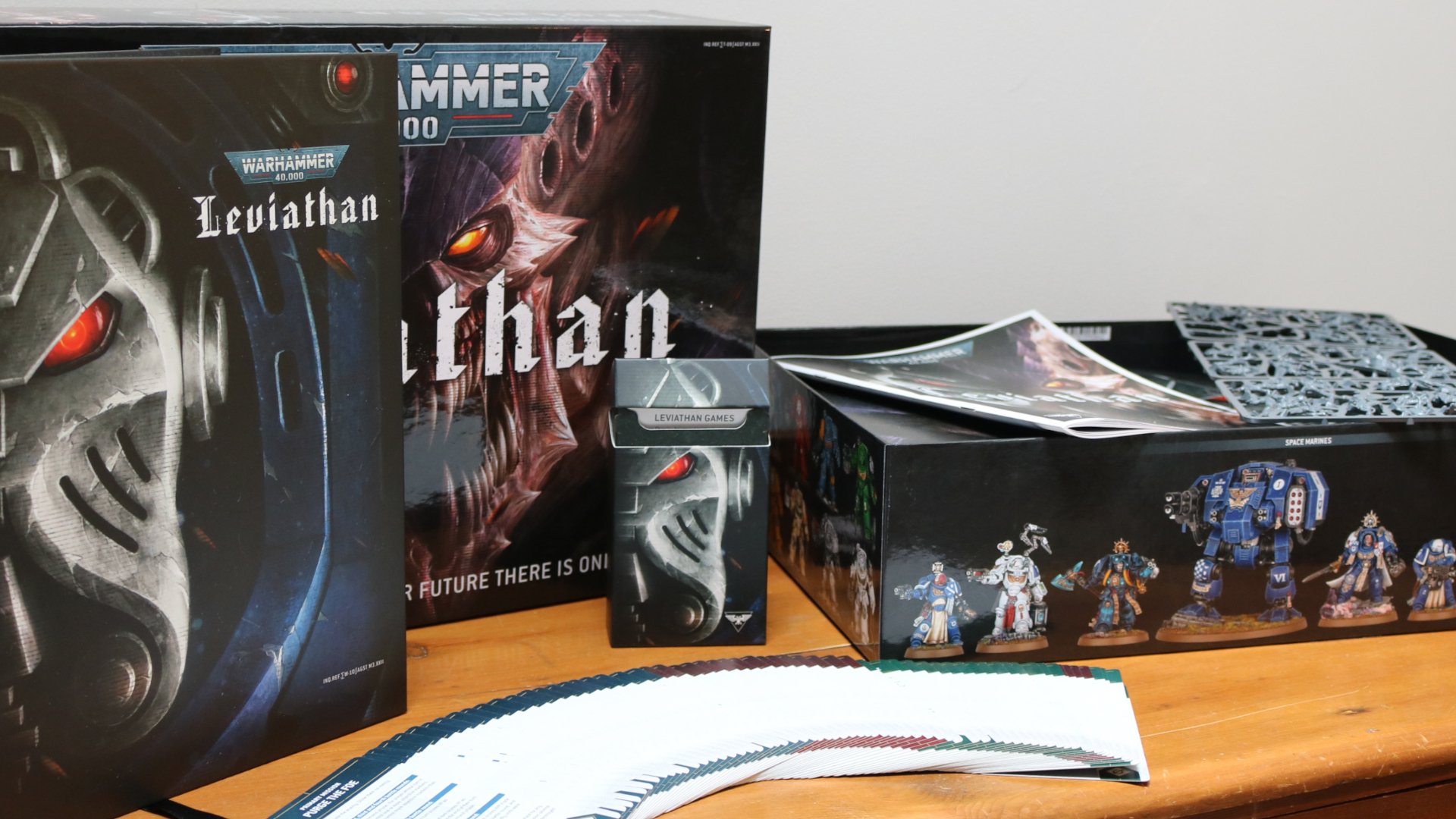 A Warhammer Open 40،000: مجموعة Leviathan Box وكتاب القواعد على طاولة خشبية ، مع بطاقات وضعت أمامه