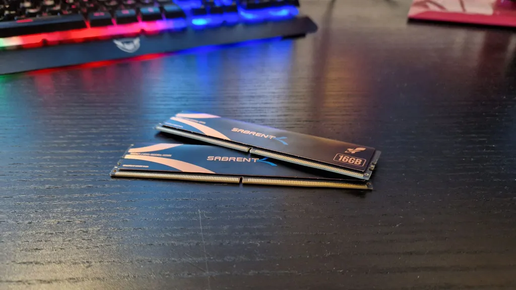 Sabrent Rocket DDR5 RAM felülvizsgálati kép 2 modult mutat, egyiket a másikra helyezve egy asztalon