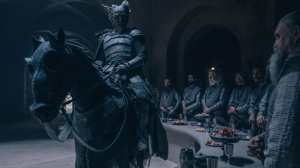 A Zöld Lovag egy lovon lovagol Artúr király udvarában a The Green Knight című filmben