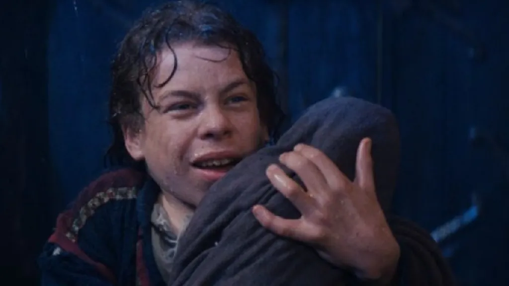 Warwick Davis egy kisbabát tart a kezében a Disney Willow című filmjében.