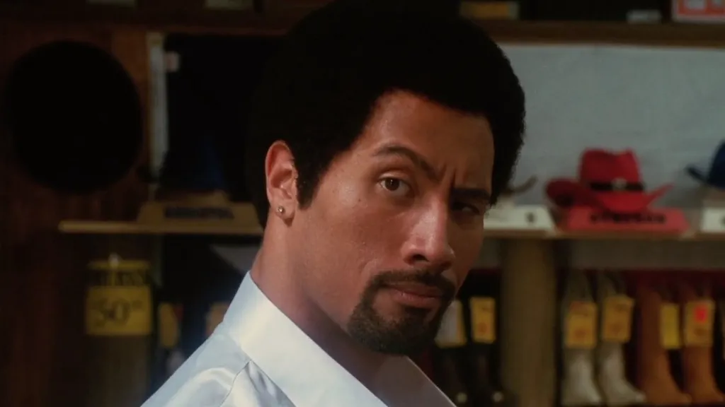 Dwayne Johnson felhúzza a szemöldökét, miközben afro frizurát visel a Be Cool című vígjátékban.