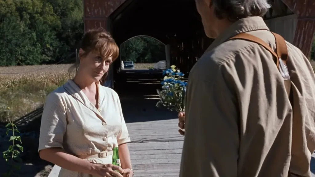 Clint Eastwood virágot kínál Meryl Streepnek egy napsütéses mezei séta közben a The Bridges of Madison County című filmben.