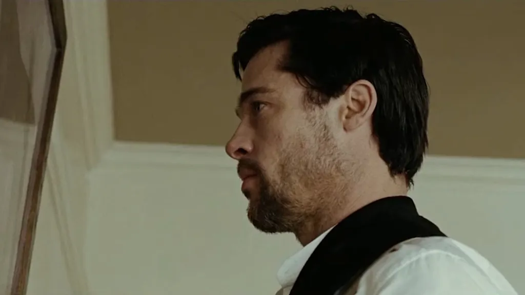 Jesse James rolündeki Brad Pitt, The Assassination of Jesse James by the Coward Robert Ford filminde tozlu bir resmi temizlemek için bir sandalyenin üzerinde duruyor